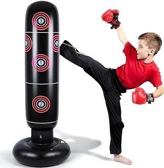 Enfant en gants de boxe rouges donnant un coup de pied à un punching ball gonflable noir avec des cibles rouges et blanches
