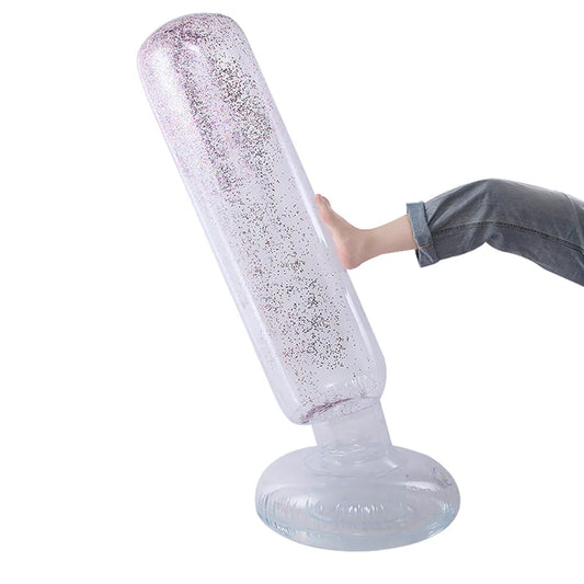 Personne frappant un punching ball gonflable transparent avec des paillettes multicolores, démontrant sa flexibilité et sa capacité à se redresser.