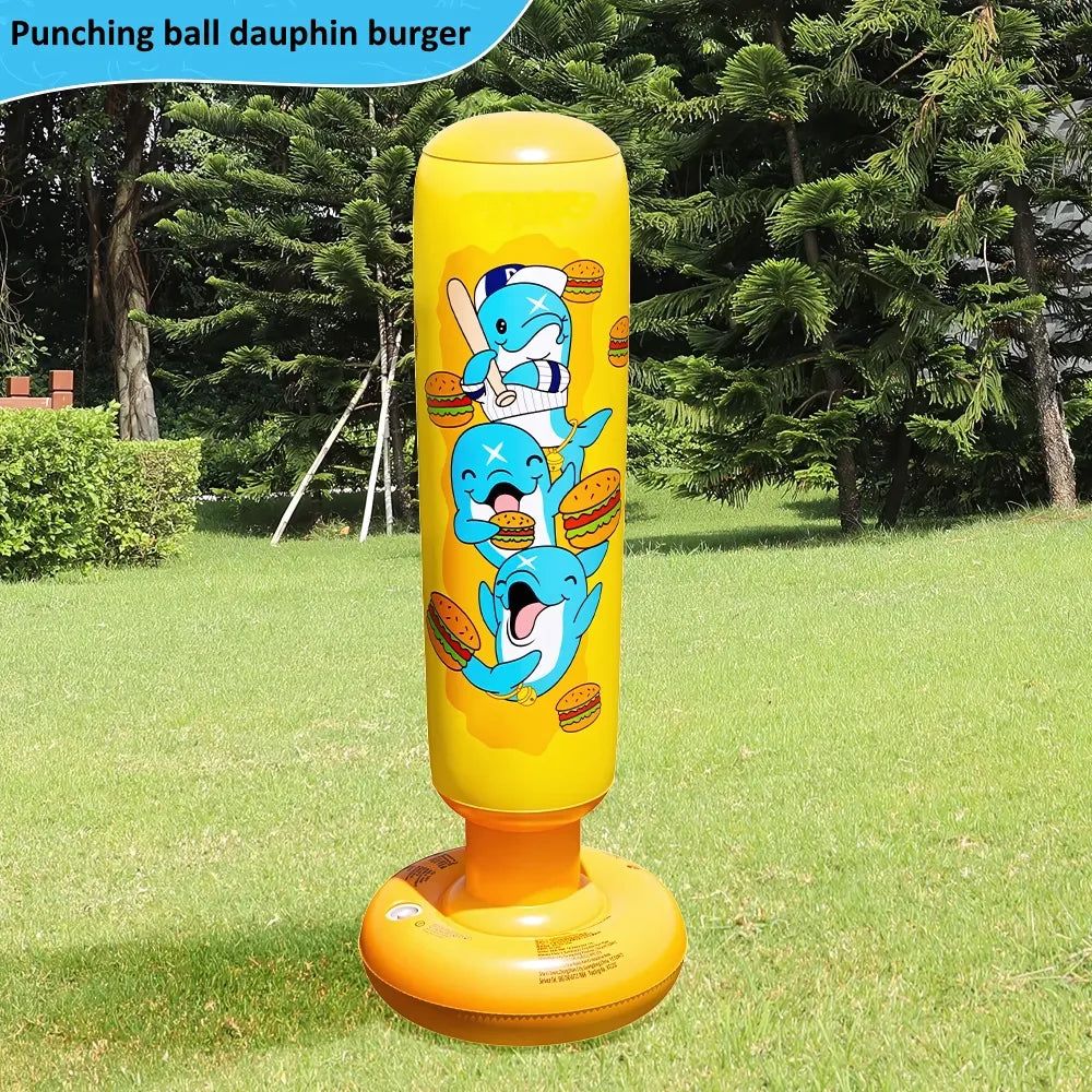Punching ball jaune avec dauphins mangeant des burgers, posé sur l'herbe dans un jardin.