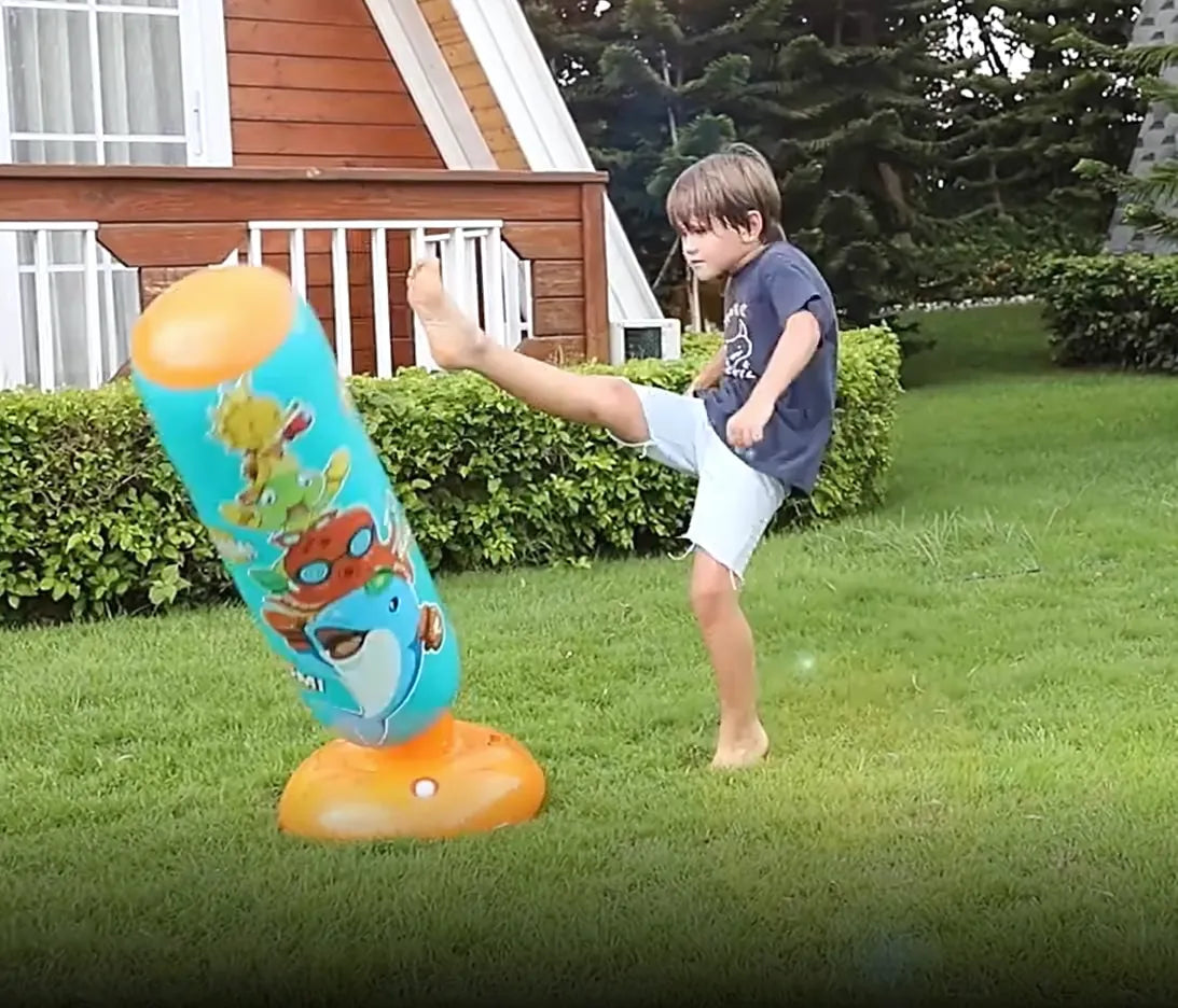 Enfant frappant un punching ball gonflable bleu avec le pied.