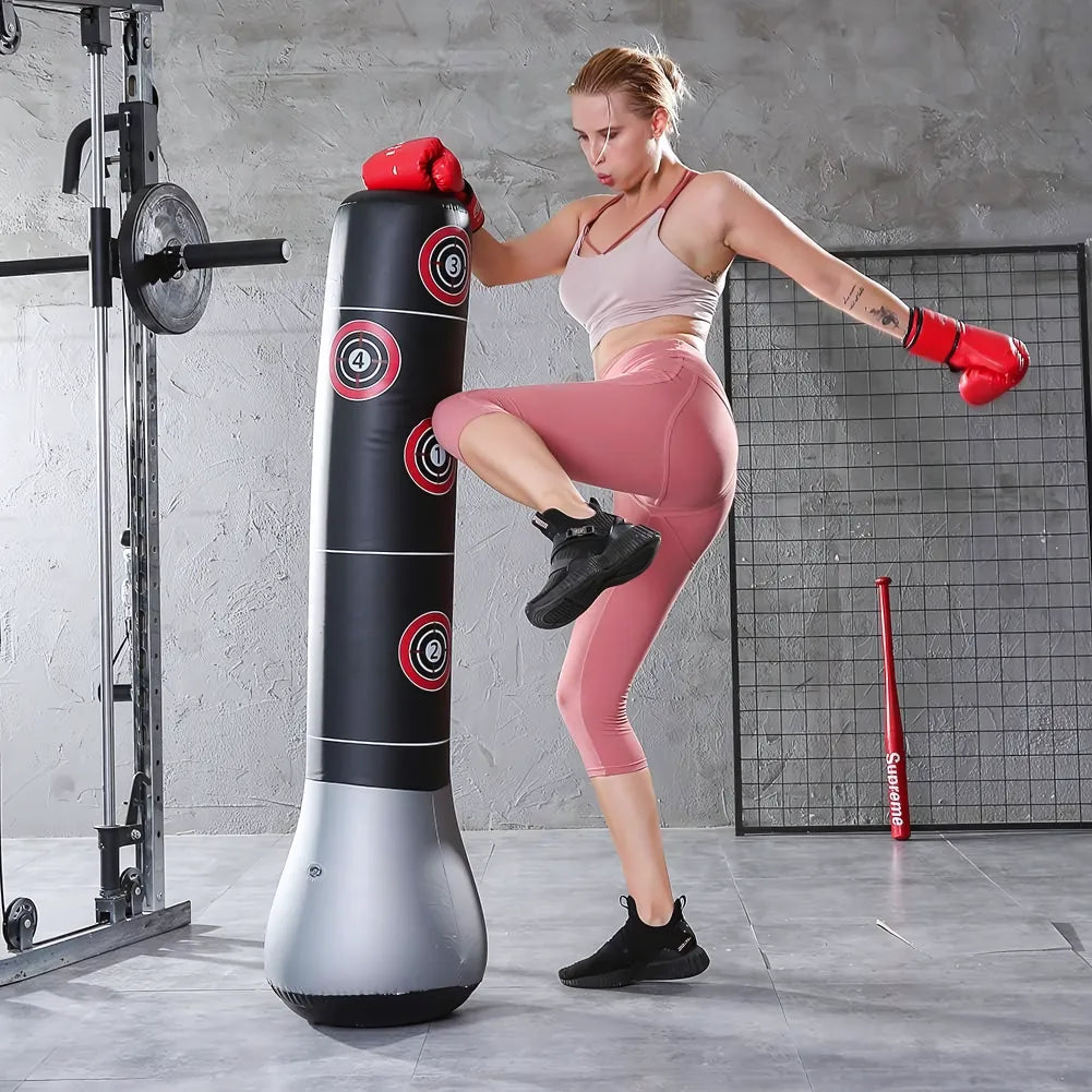 Femme s'entraînant avec un punching ball gonflable noir dans une salle de sport.